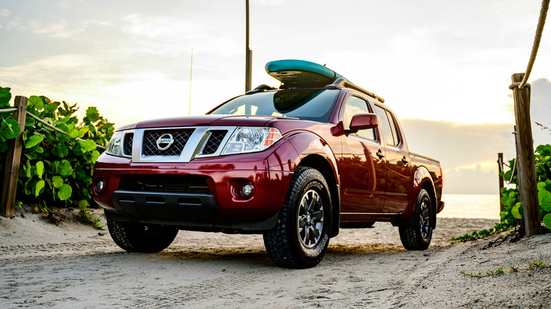 A front end shot of a red 2021 Nissan Frontier on a beach