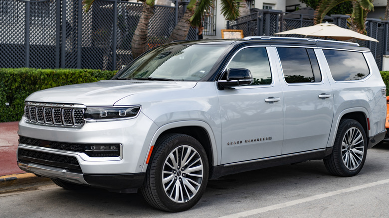 A gray 2024 Jeep Grand Cherokee parked at the side of a small road.