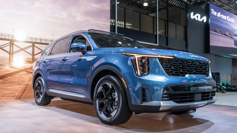A light metallic blue Kia Sorento Hybrid SUV from the current generation parked indoors at a show.