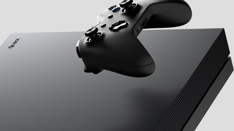 A black Xbox controller floats above the vent of a black console.