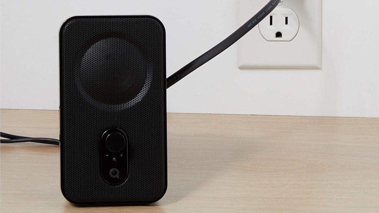 Black computer speaker plugged into wall