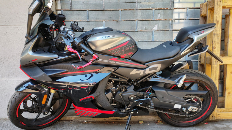 A black and red CFmoto-manufactured sport bike standing on its kickstand in the shade.