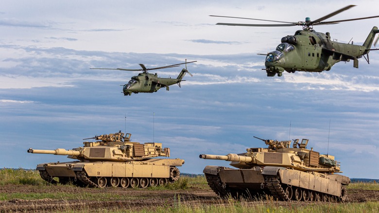 The photo depicts a powerful combination of American M1 Abrams tanks Mi-24 helicopters, which have been deployed to support the Ukrainian military in their ongoing conflict