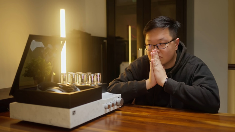 Crinacle with palms pressed together looking at expensive headphones