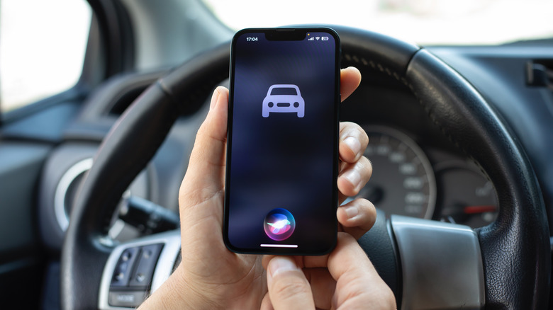 A person holding an iPhone in a car while activating Siri
