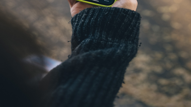 A woman's handing holding a phone displaying the Waymo app