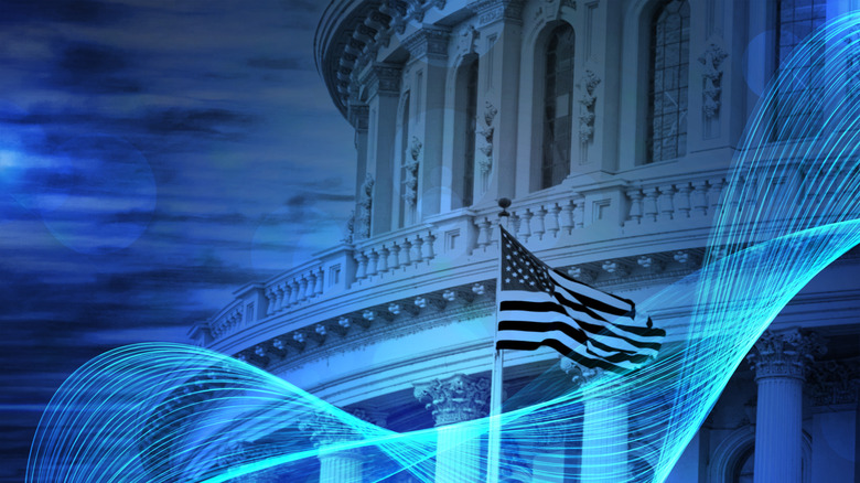 A zoomed-in image of the U.S. capitol with the American flag in front of it.