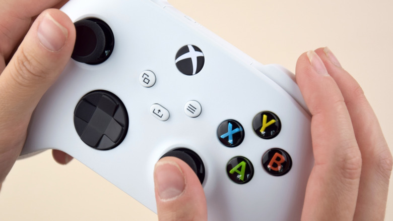 A close up of hands holding a white Xbox controller