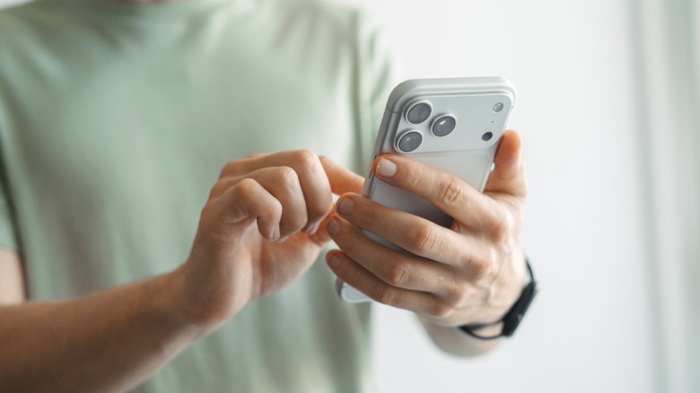 Personin a green t-shirt using an iPhone 17 Pro