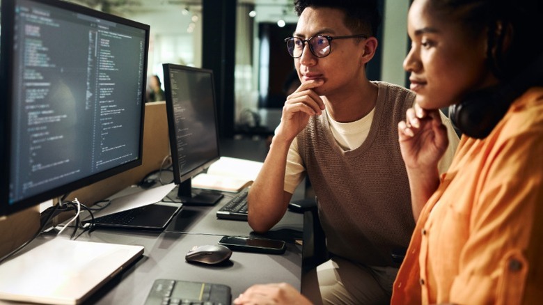 Two people reviewing code on a monitor