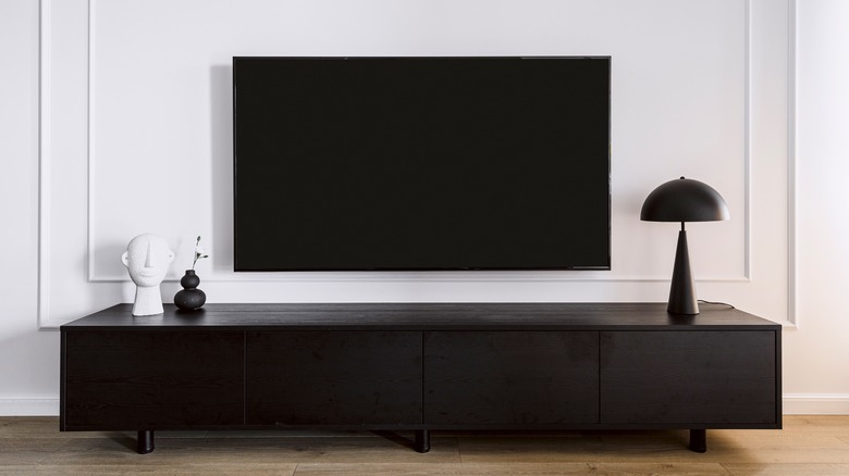 a mounted TV hanging above a media cabinet