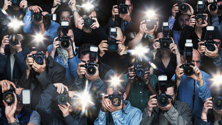 large group of photographers taking photos with flash bulbs