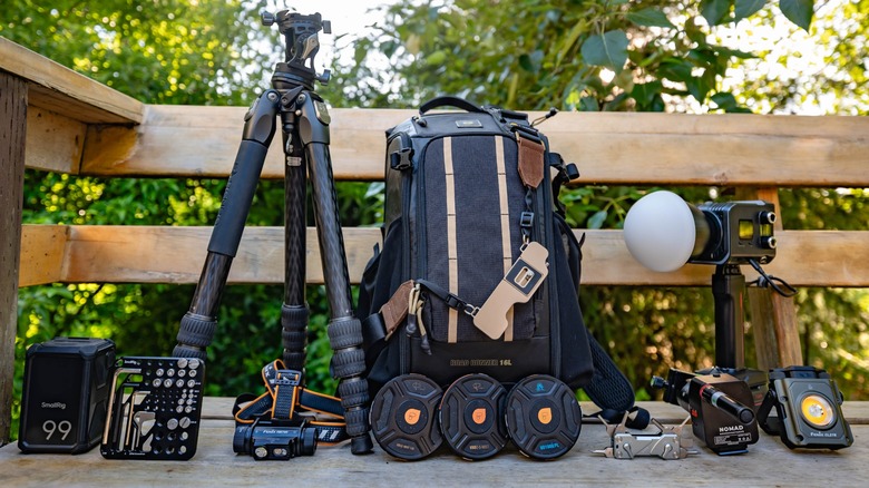 A photo featuring numerous camera accessories arranged on a wooden bench.