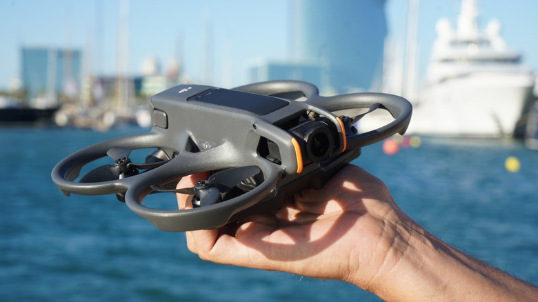 DJI Avata 2 drone being held in hand beside the sea