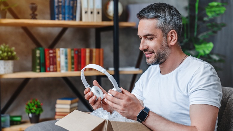 Man holding white headphones he just took out of a box