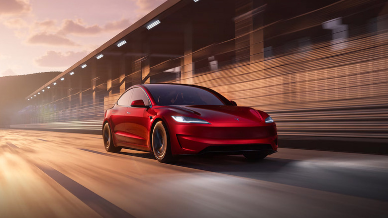 A red 2025 Tesla Model 3 Peformance driving on a racetrack