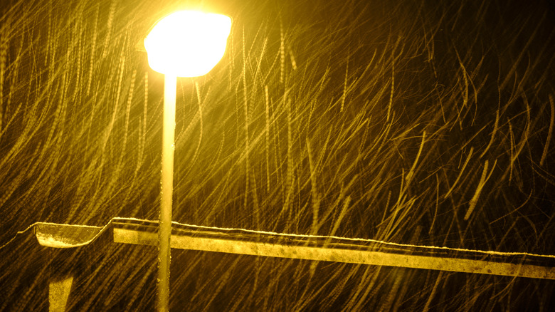 Snow falling under a yellow street light