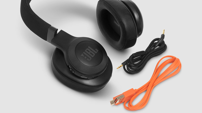 JBL headphones on a white surface next to charging cables