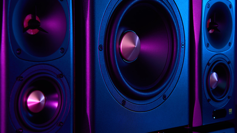 Two sound speakers and subwoofer on dark background with neon lights