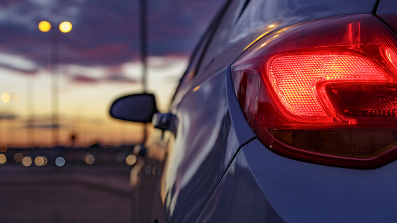 Lit taillight of a car on the road at dusk