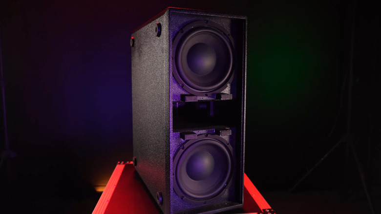 A still of a Rockville Audio subwoofer loudspeaker in a dark room on a red box.