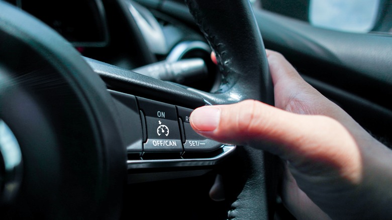 Driver using steering wheel buttons to turn on cruise control.