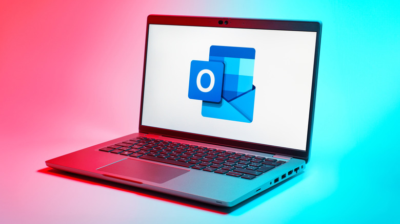 Laptop showing Outlook logo on a bright pink and turquoise background