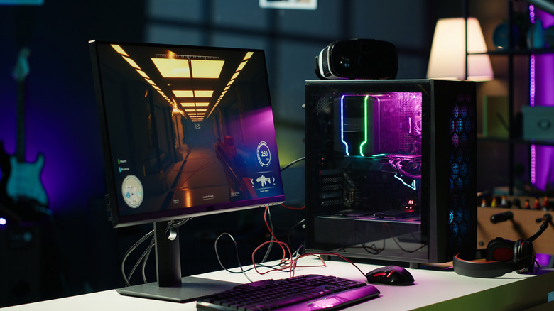 A gaming PC on a white desk with colorful lights coming from the case.