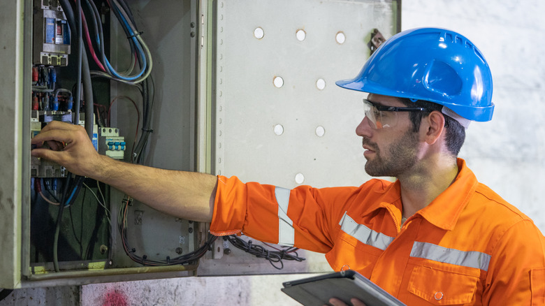 An electrician working at electrical panel breaker switch