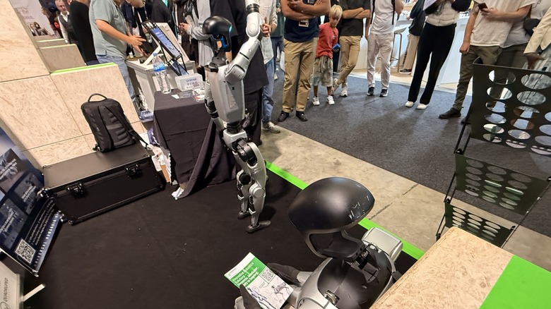 Humanoid robot reading a pamphlet as another humanoid robot waves at the crowd