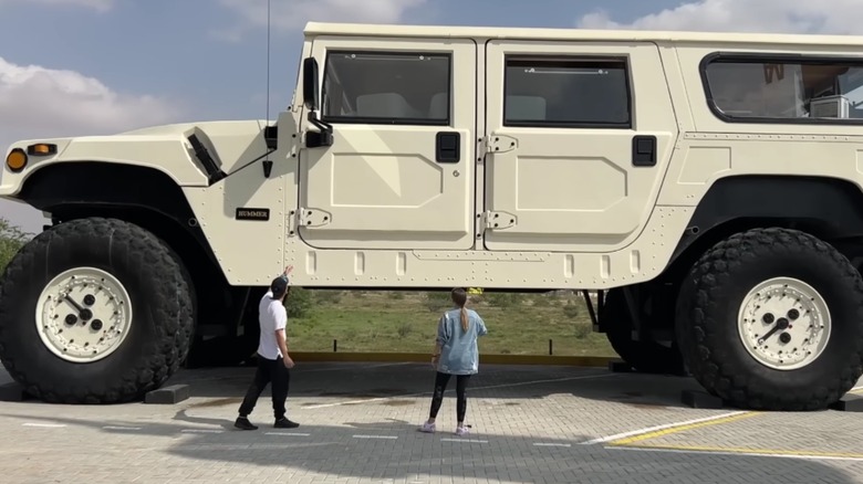 Two people look up at the huge Hummer H1 X3.