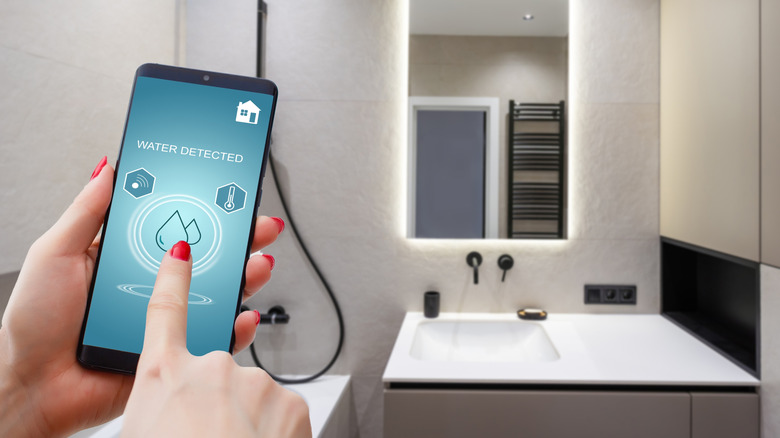 Receiving a water leak alert on a smartphone in the bathroom.