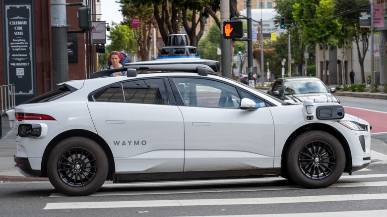 A side view of a Waymo robotaxi driving down the street
