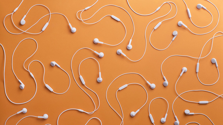 multiple sets of earbuds against orange background