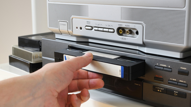 Person inserts VHS tape into player.