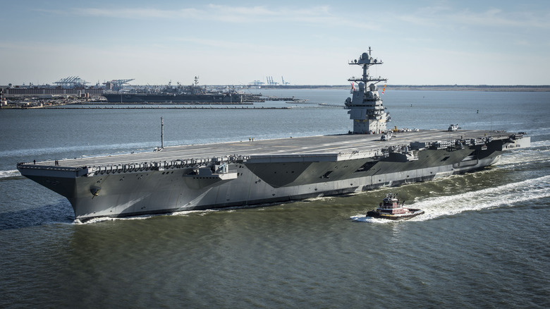 An aircraft carrier with a smaller vessel alongside.