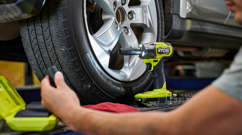 A man working on a car with a Ryobi impact wrench