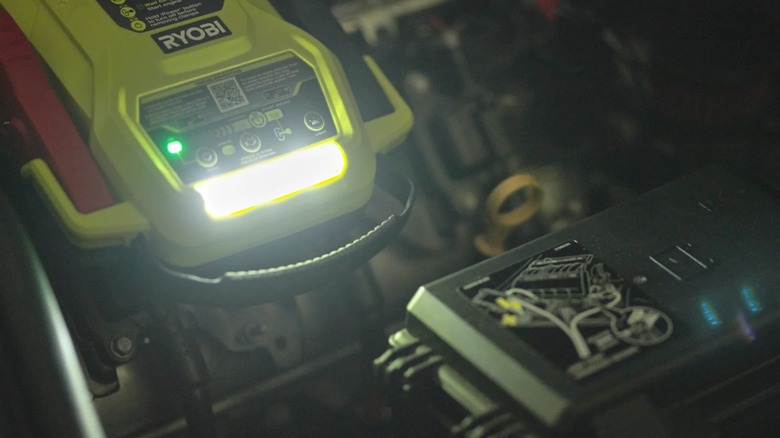 Ryobi 18V One+ Jump Starter resting on an engine with LED light turned on
