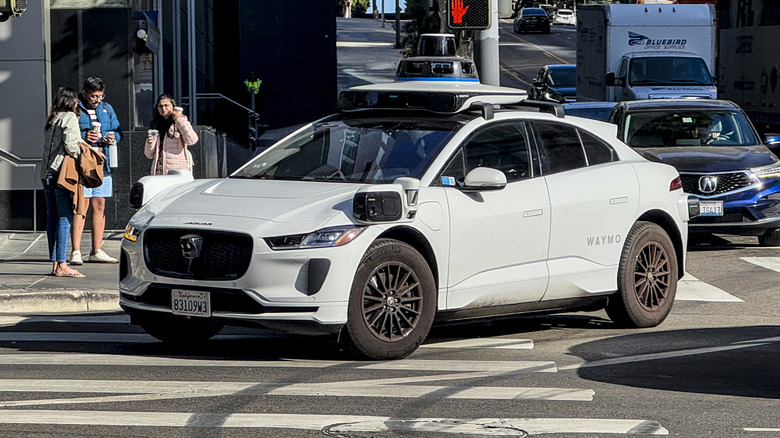 A Waymo autonomous taxi picks up passengers in Downtown Los Angeles