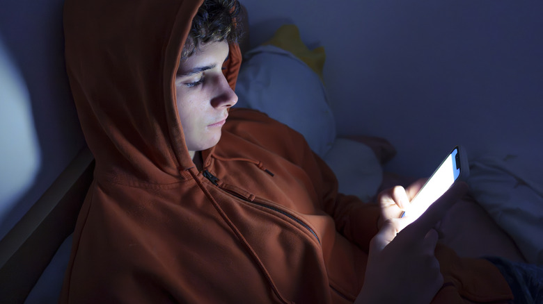 Teenager using a smartphone lying in bed