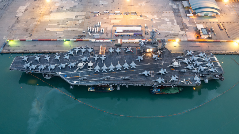 An aircraft carrier with a lot of aircraft on its deck.