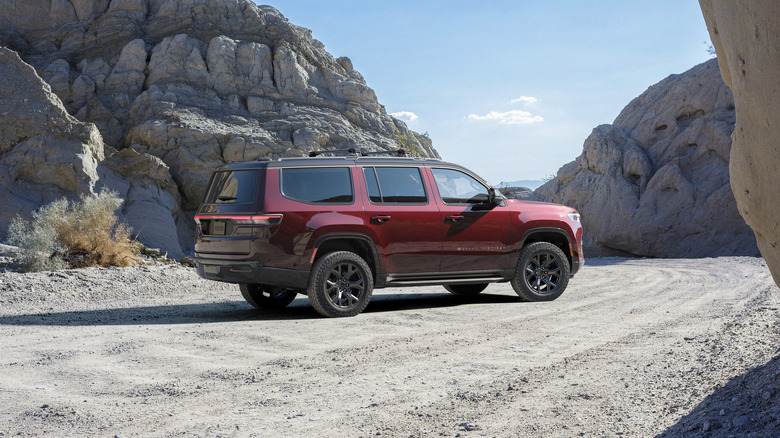 right side view of Red Jeep Grand Cherokee parked in dirt among rock formations