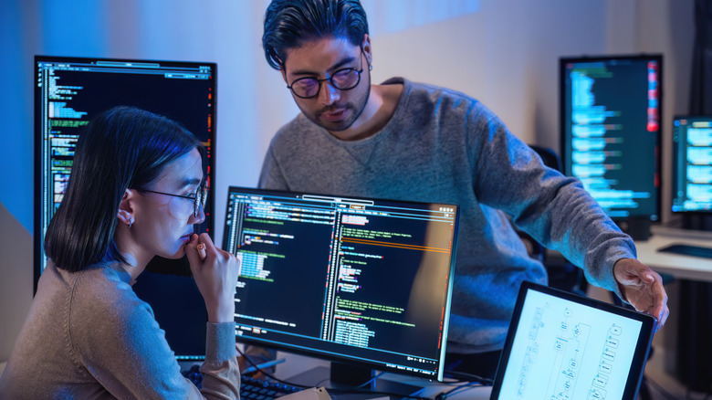 Programmers looking at code and flowcharts on multiple screens