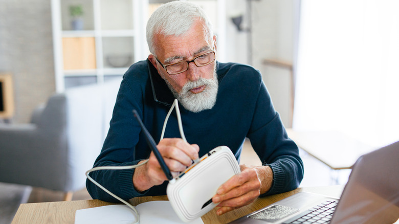 A senior man mking a phone call while holding a router