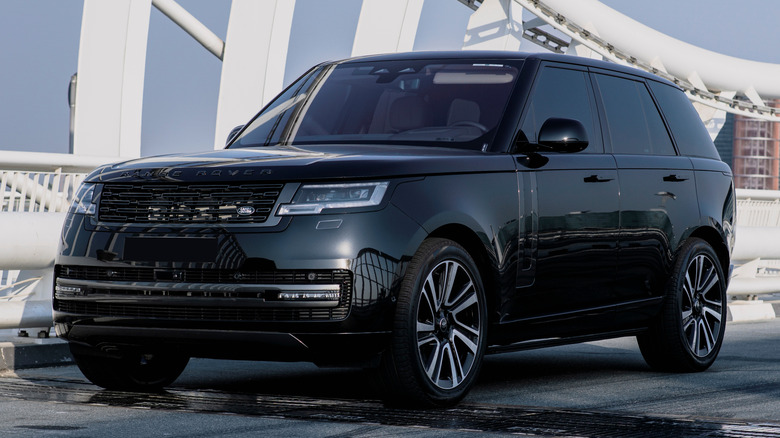 A black Range Rover Vogue parked outside with white shapes around it.