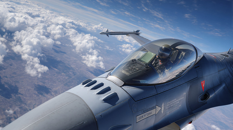 Close-up of pilot inside F-16 Falcon as it flies above the clouds.