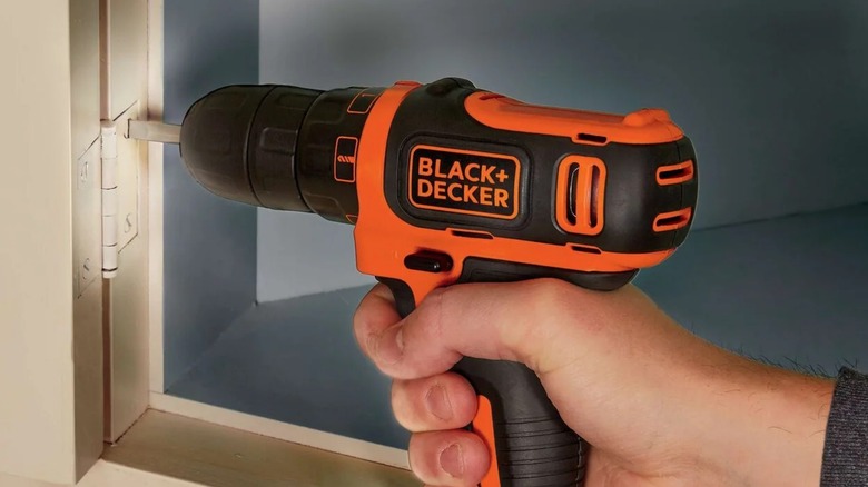 Person using Black and Decker drill on hinge