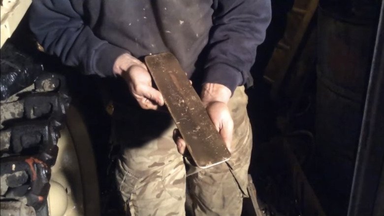 Todd Chamberlain holds gold bar taken from inside of an old tank