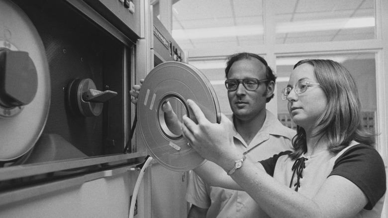 A student holding a spool of magnetic tape