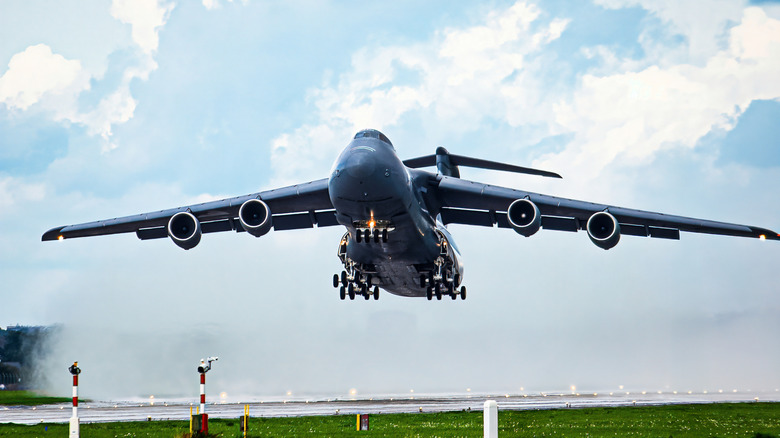 Large four-engine cargo plane landing on a runway.